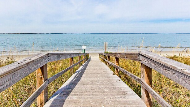 A wooden boardwalk leading to a beach with a clear view of the water and sky. - Bay View Villas 105 | Waterfront, Community Pool (Tybee Island)