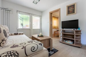A living room with a sofa, a TV, a wooden coffee table, and a bookshelf.