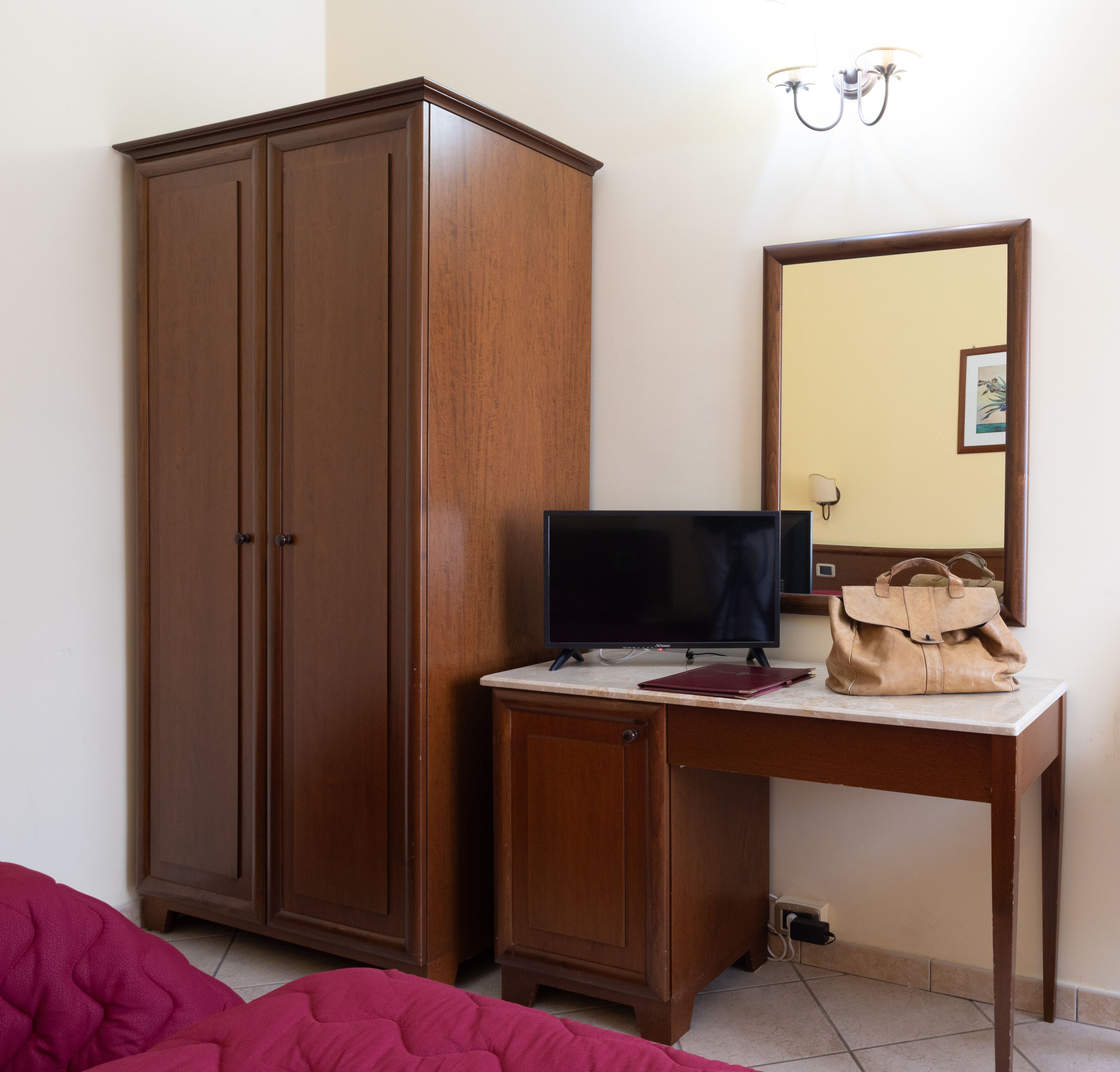 A bedroom with a wardrobe, a desk with a computer, a mirror, and a bed.