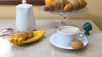 A table with a coffee cup, croissants, a cookie, and a teapot.