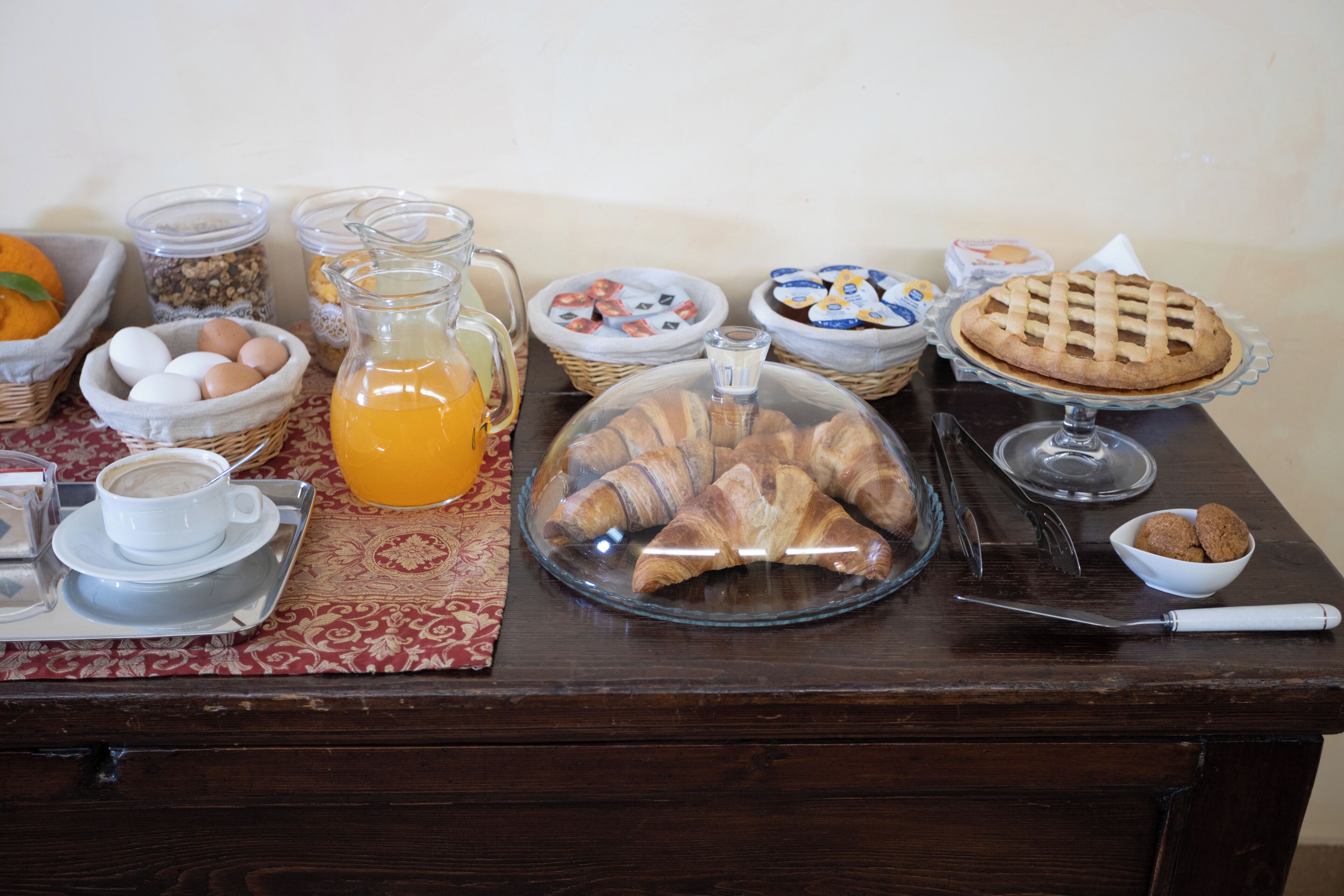 A breakfast buffet with croissants, eggs, and juice.