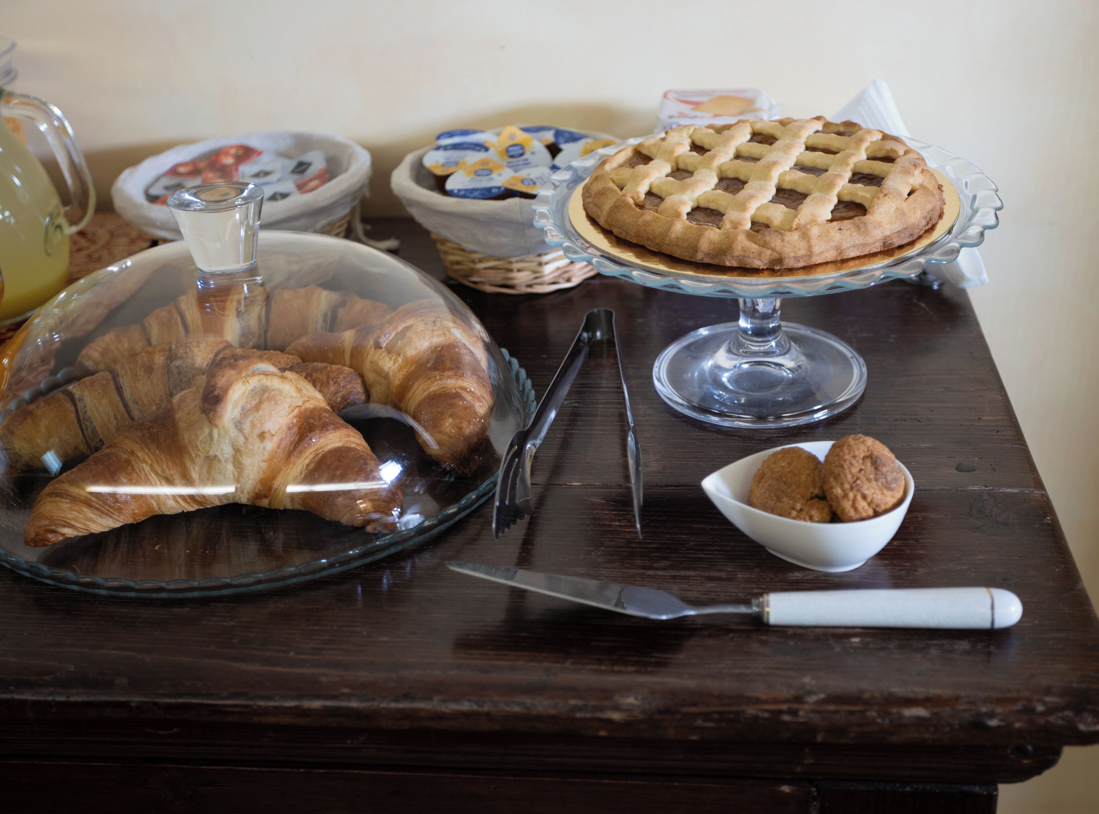 Une table de petit-déjeuner avec des croissants, une tarte et un muffin dans un bol.