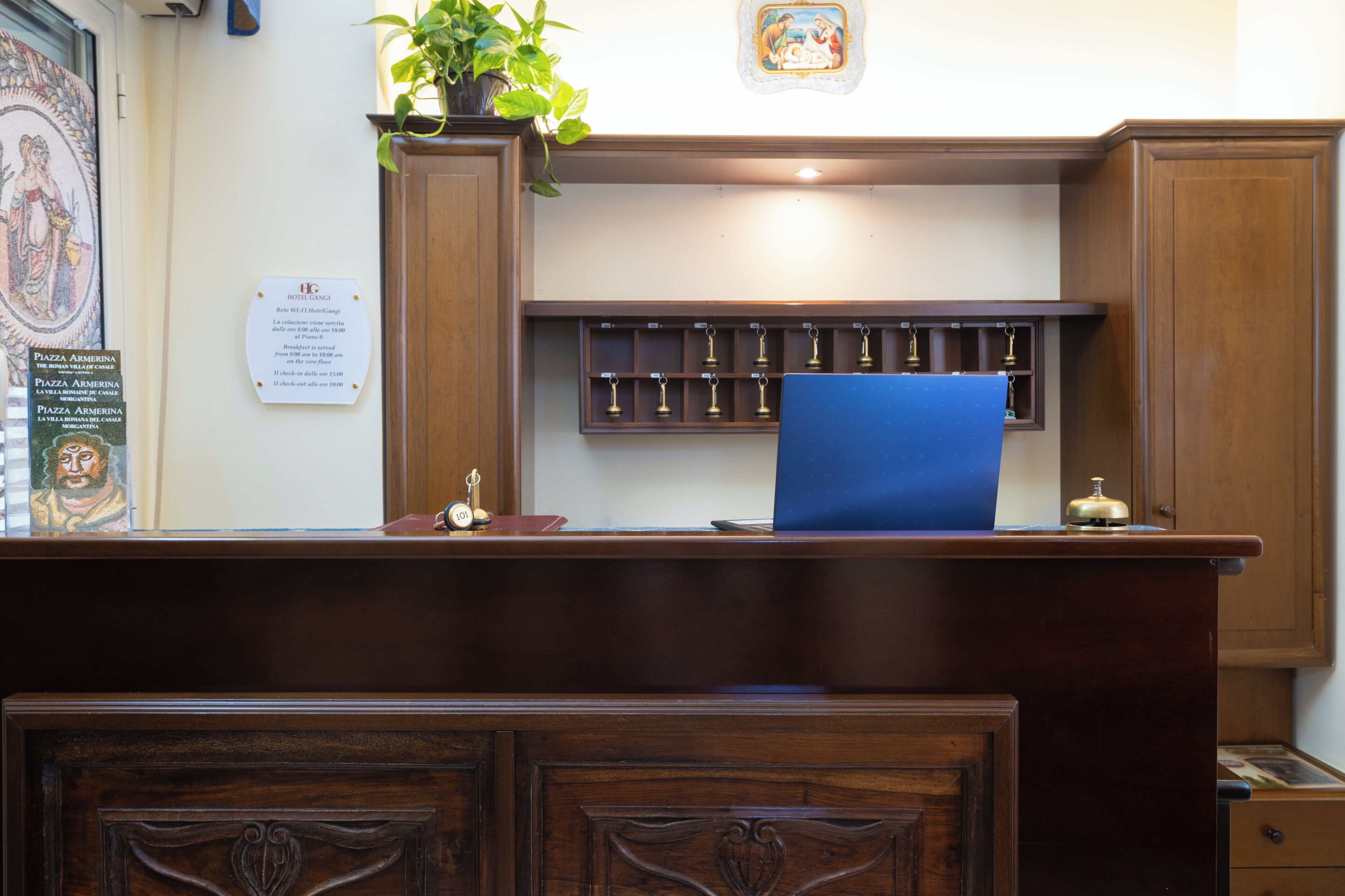 A reception desk with a blue chair, wooden cabinets, a plant, and a wall-mounted display case.