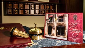 A model of Hotel Ganghi with a detailed miniature of the building, a brass bell, and a red book with the hotel name. - Hotel Gangi (Piazza Armerina)