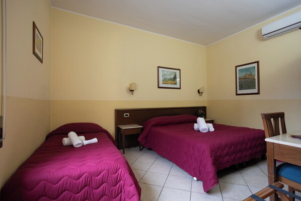 A hotel room with two beds, a desk, and a chair. - Hotel Gangi (Piazza Armerina)