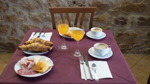 A table set with croissants, toast, ham, cheese, and a cup of coffee, with two glasses of orange juice. - Hotel Gangi (Piazza Armerina)