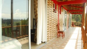 A balcony with a view of a forested landscape, a brick wall, and a wooden railing.