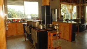 A kitchen with a large stove, wooden cabinets, and a window overlooking greenery.