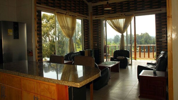 A spacious kitchen with a large island, dining area with chairs and a table, and a balcony with a view of the outdoors.