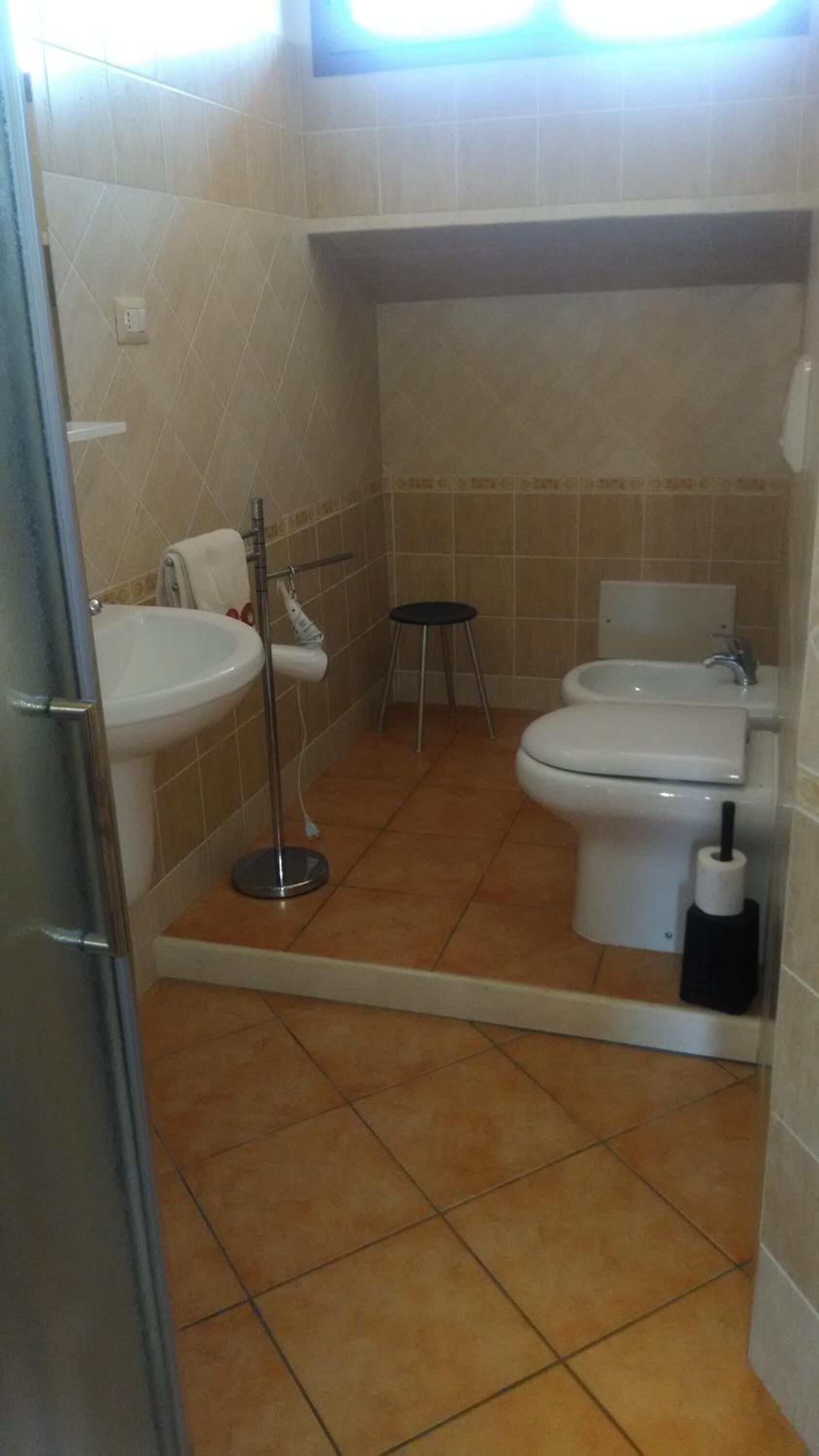 Ein Badezimmer mit zwei Toiletten, einem Waschbecken und einem Spiegel.