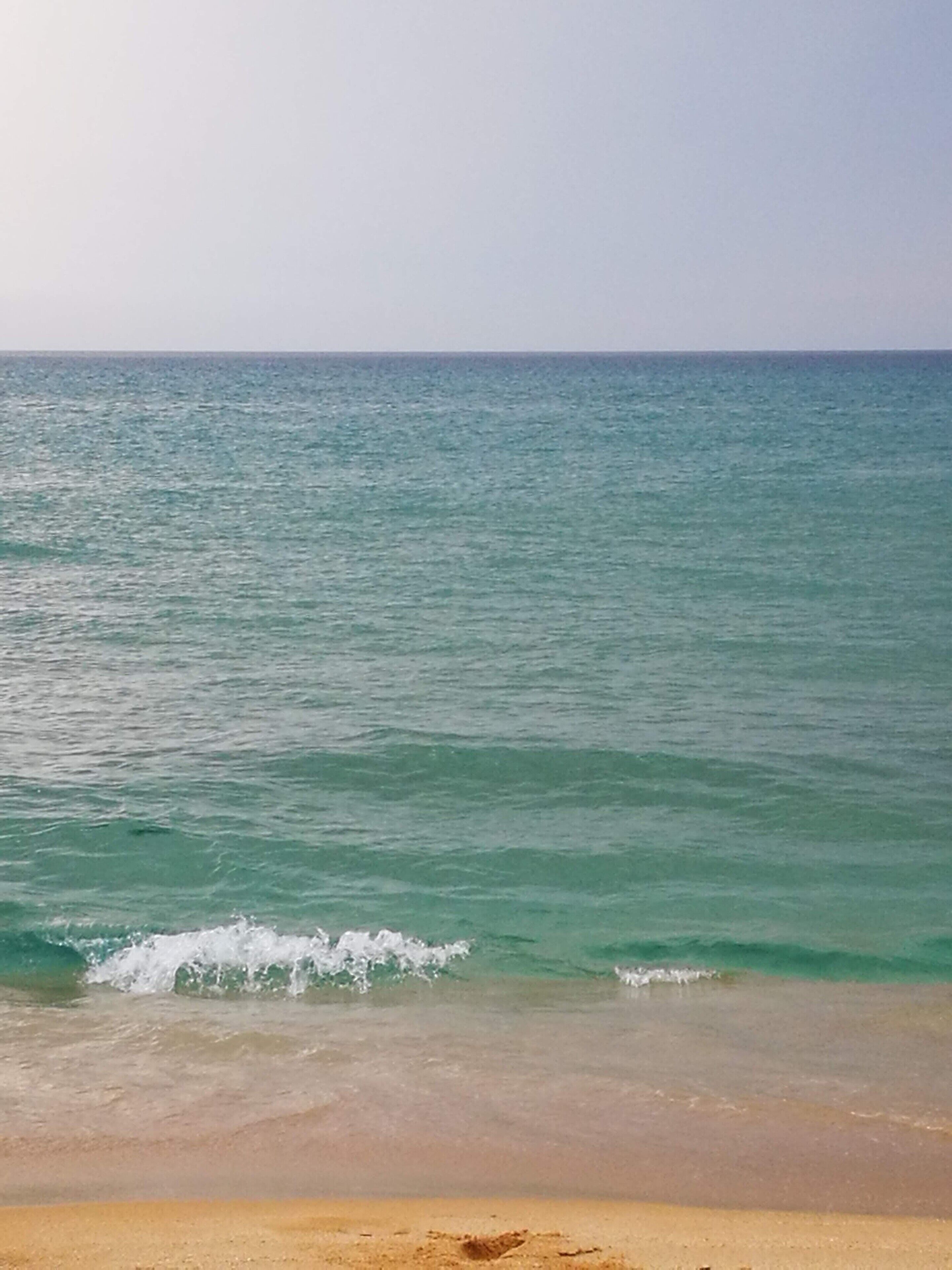 A beach with clear turquoise water and a sandy shore.