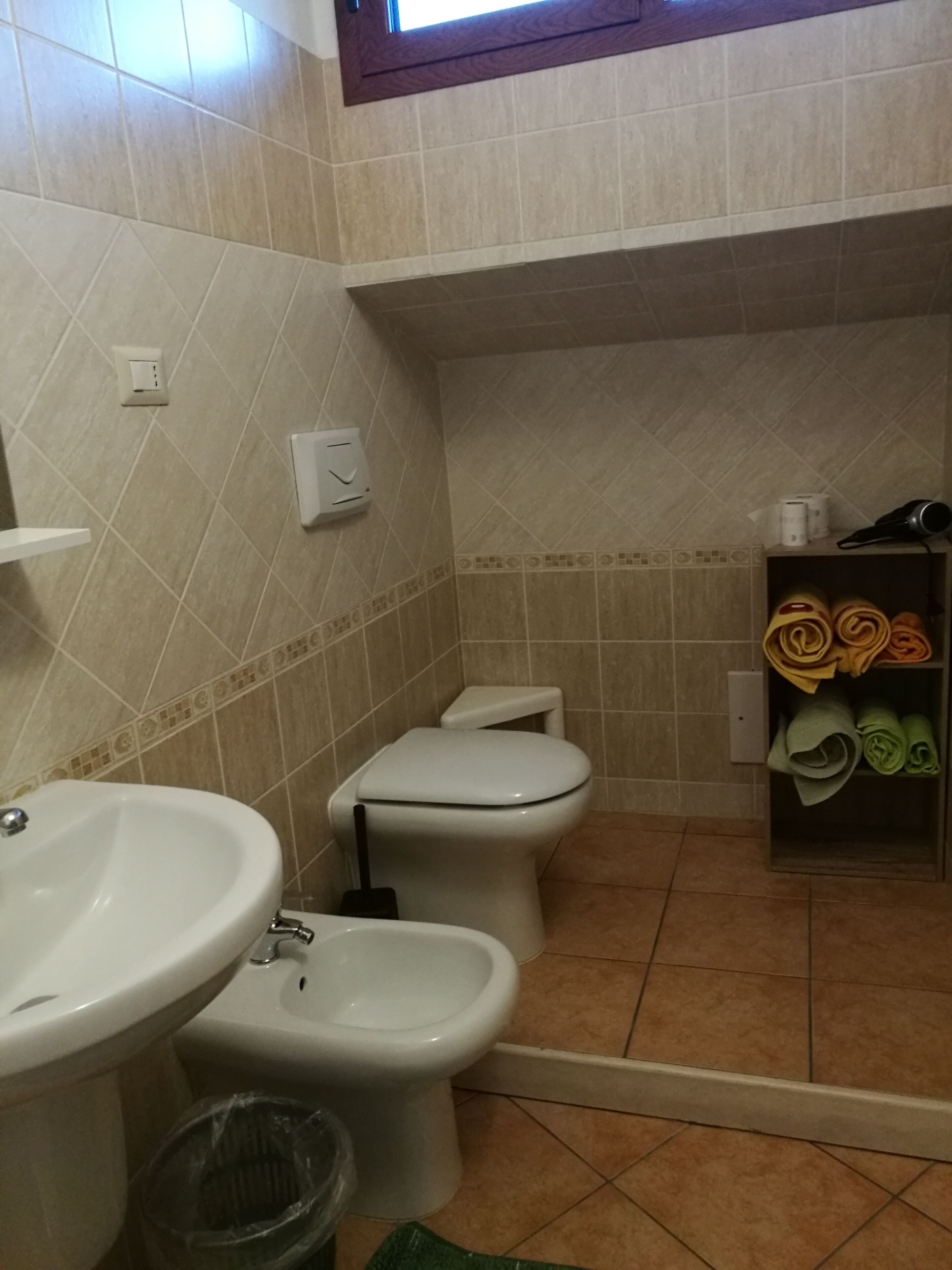 Ein Badezimmer mit Waschbecken, Bidet, Toilette und Ablage für Handtücher.