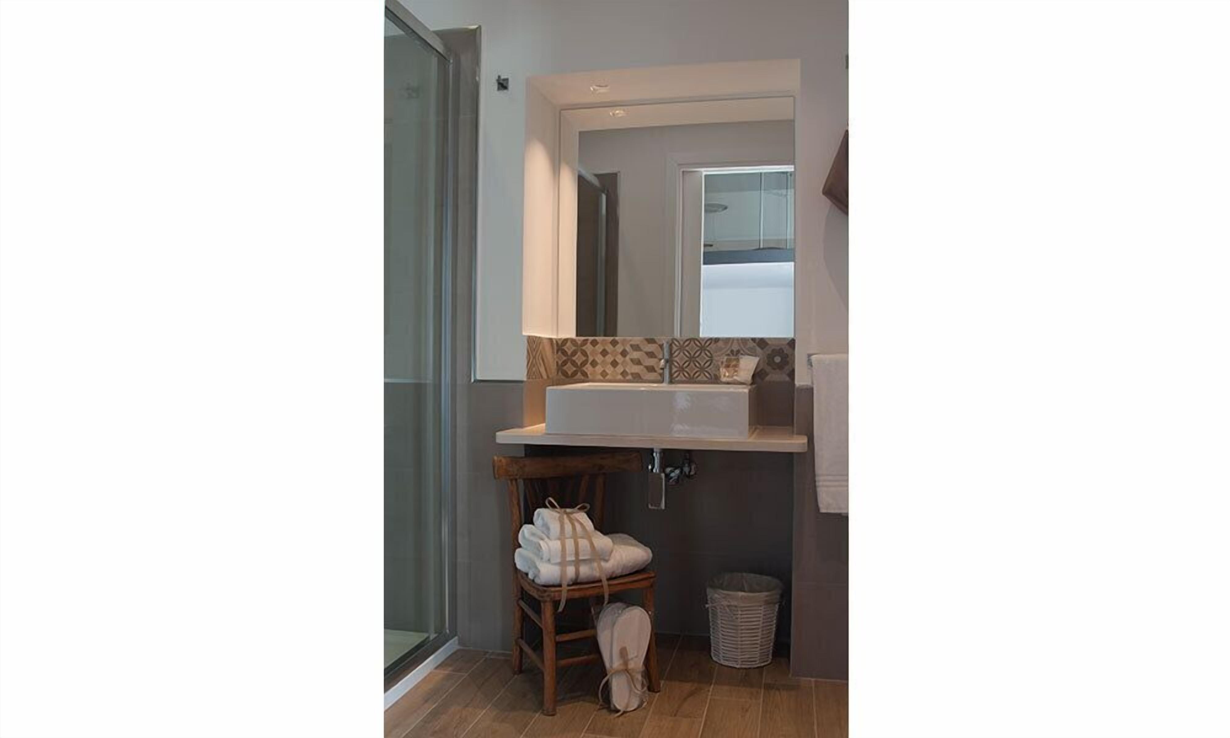 A bathroom with a large mirror, a sink, and a towel rack.