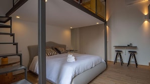 Ein modernes Schlafzimmer mit einem Bett, einer Treppe und einem kleinen Tisch mit Hocker.