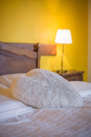 A bed with a fluffy pillow and a lamp on a bedside table.