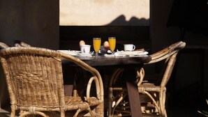 Ein Korbstuhl-Set mit Frühstücksangeboten, darunter Eier und Orangensaft, draußen mit Blick auf Berge.