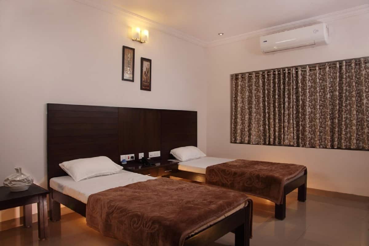 Une chambre d’hôtel avec deux lits, une table de chevet, une lampe, un vase décoratif et un rideau à motifs.