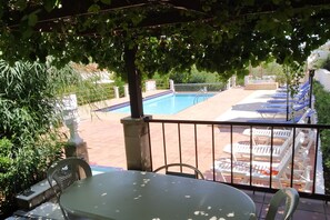 A pool area with lounge chairs and a table under a shaded pergola. - Villas Eva with Panoramic Sea view (Chania)