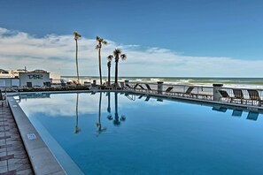A pool with a view of the ocean, palm trees, and a building labeled "DBR". - Daytona Beachfront Condo w/ Ocean View (Daytona Beach)
