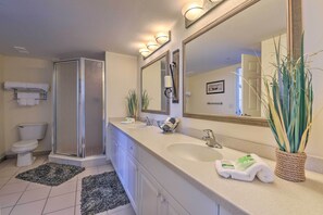 A modern bathroom with a walk-in shower, a large vanity with a sink, and a mirror. - Daytona Beachfront Condo w/ Ocean View (Daytona Beach)