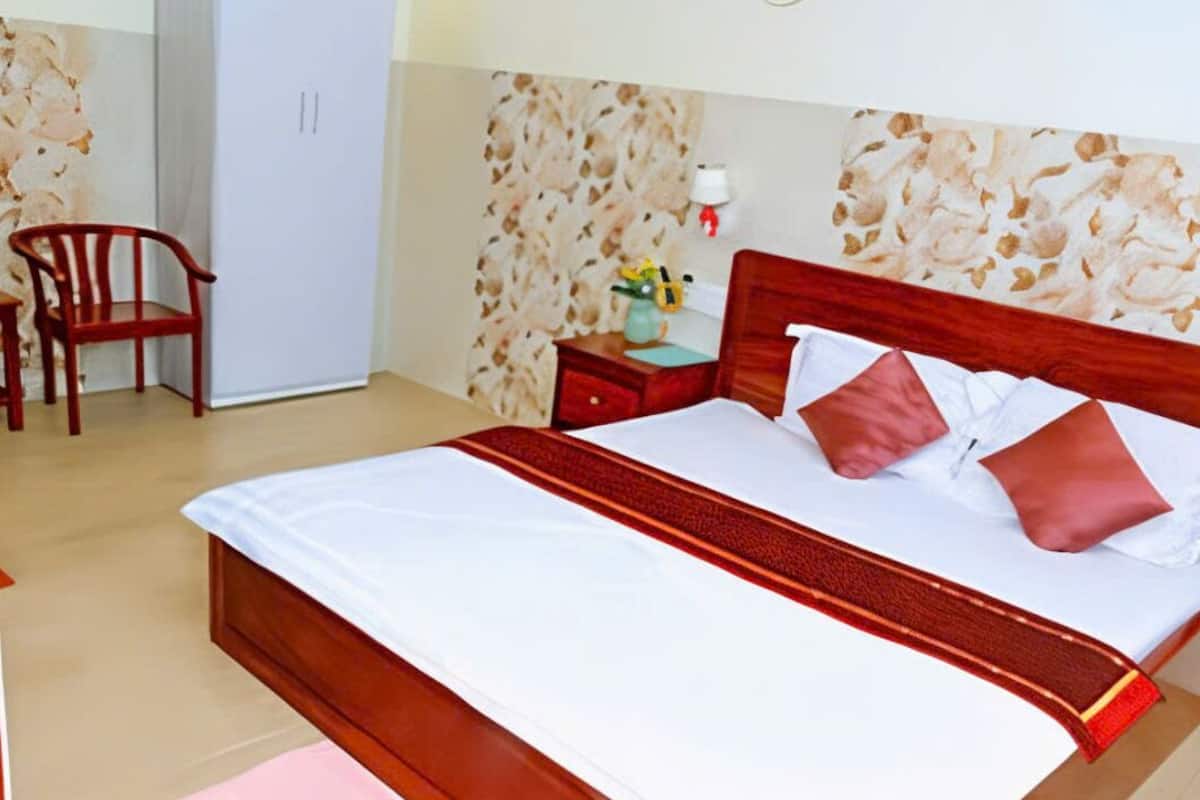 A neatly arranged bedroom with a large bed, a wooden nightstand, a chair, and a wardrobe.