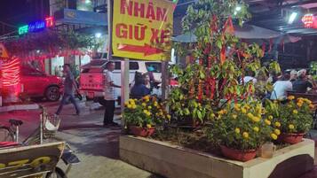 A street scene with a neon sign for a restaurant, a bicycle, and potted plants.