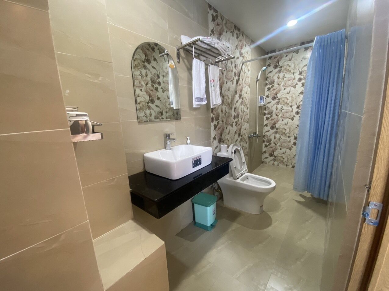 Un baño moderno con lavamanos blanco, inodoro, zona de ducha y cortina azul.