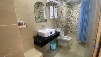 Un baño moderno con lavamanos blanco, inodoro, zona de ducha y cortina azul.