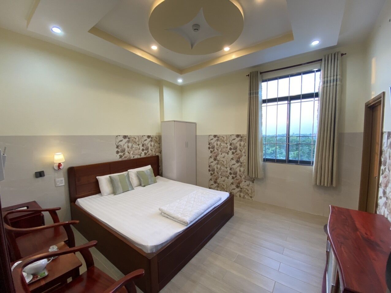 Een hotelkamer met een groot bed, een bureau, een kledingkast en een raam met gordijnen.