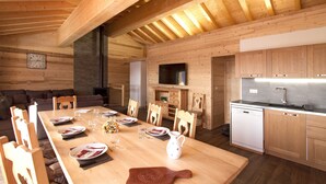 A wooden interior with a dining table set for four, a kitchen with modern appliances, and a cozy seating area. - Chalet Privé,  proche de la Navette (Les Menuires)