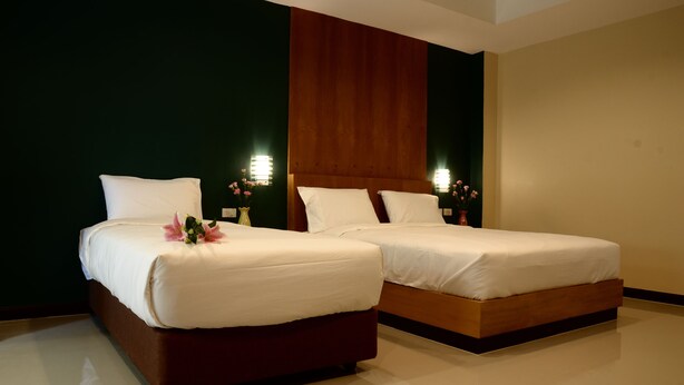 Two beds with white linens, wooden headboards, and bedside lamps with flowers. - BB Residence (Pattaya)