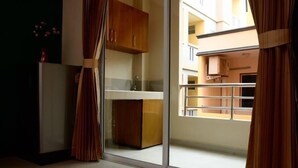 A modern kitchen with wooden cabinets, a stainless steel sink, and a sliding glass door leading to a balcony with a metal railing. - BB Residence (Pattaya)