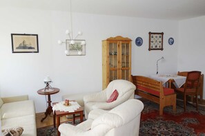 Un salon comprenant un canapé, un meuble en bois, une table avec une lampe et une chaise.