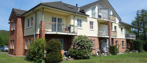 Ein zweistöckiges Wohnhaus mit Balkon, Garage und gepflegtem Rasen.