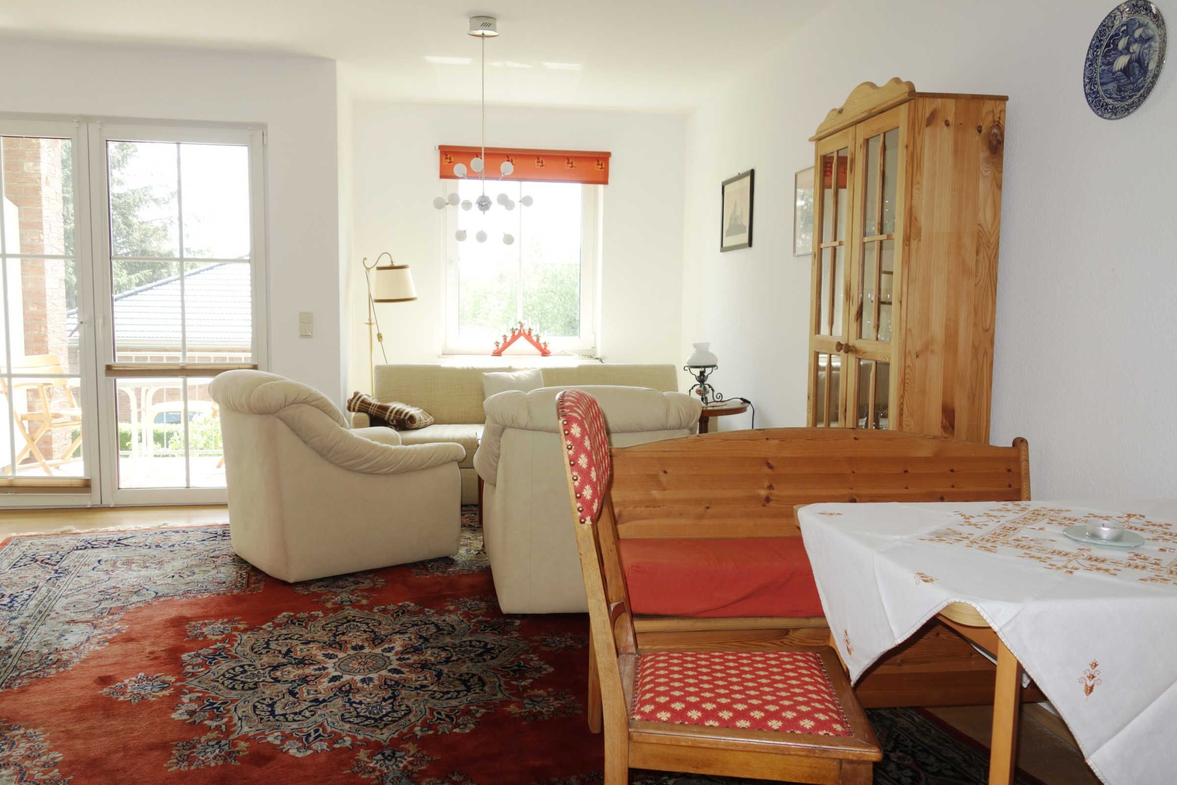 A room with a sofa, a wooden chair, a dining table, and a cabinet.