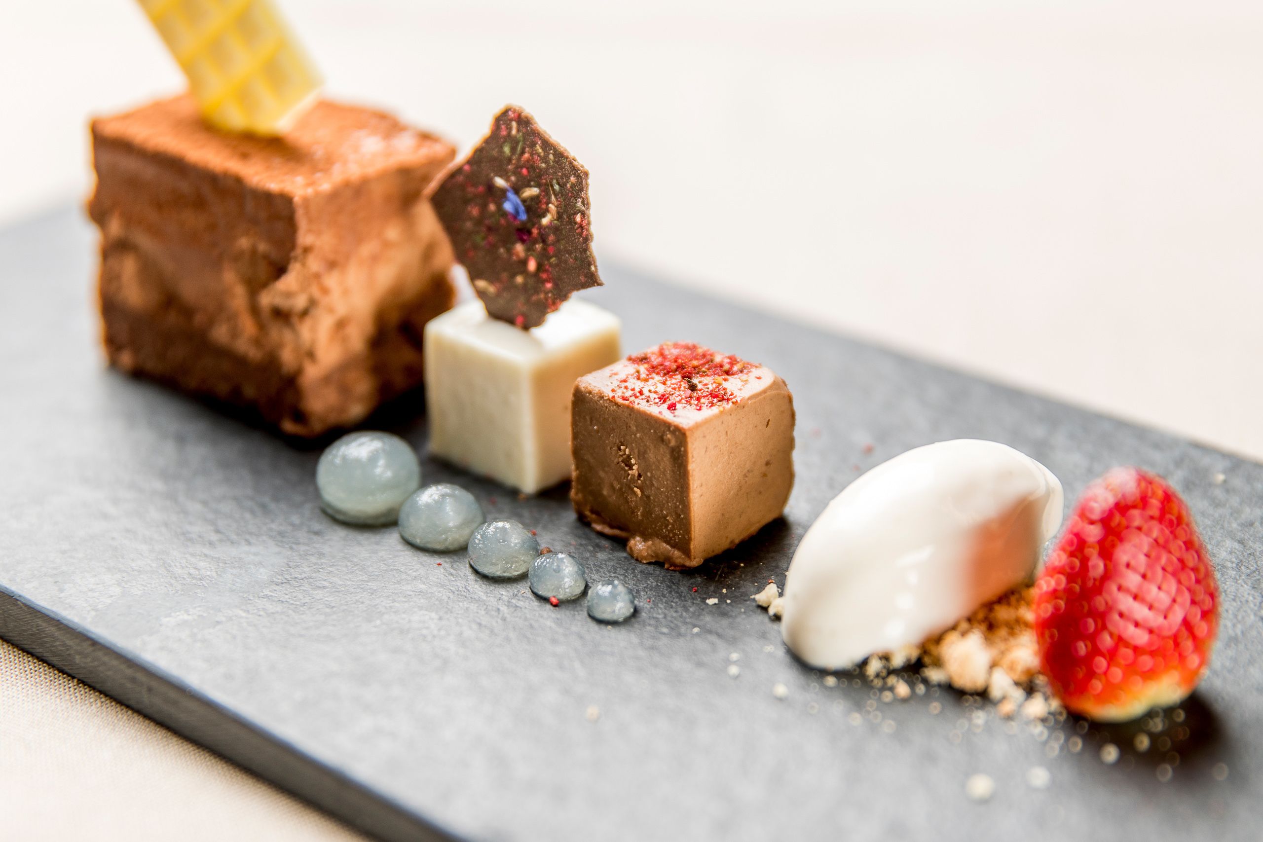 Un plato de postre con diversas golosinas de chocolate y un cono de gofre.