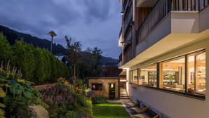 A modern building with a well-maintained garden, a wooden structure, and a staircase leading to an upper level. - Post Hotel (See)