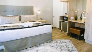 Une chambre moderne avec un grand lit, des tables de chevet, un bureau et un miroir.