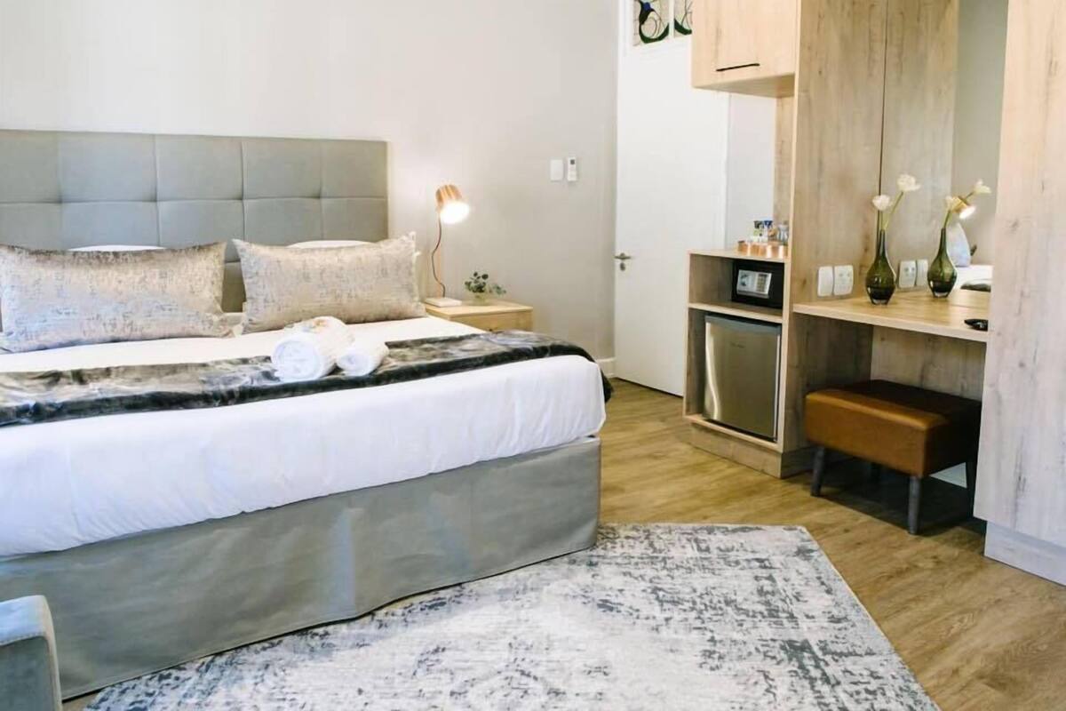 Un dormitorio moderno con una cama grande, mesitas de noche, un escritorio y un espejo.