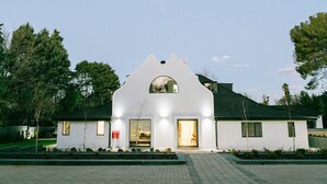 Un bâtiment moderne aux lignes épurées, d’une blancheur éclatante, qui se distingue par son architecture originale, notamment grâce à une fenêtre centrale en arc de cercle et une façade symétrique.