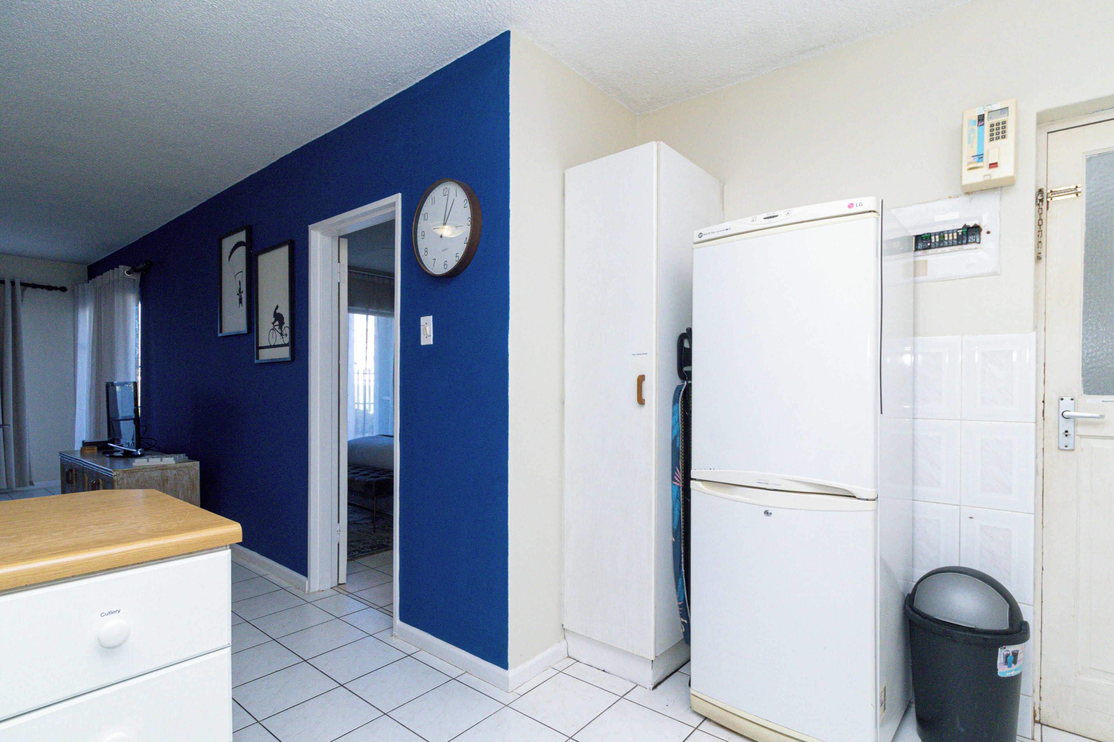 A kitchen with a white refrigerator, a wooden countertop, and a blue wall.