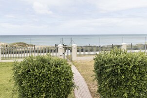 Uma passagem pavimentada que leva a uma área murada, com vista para o mar.