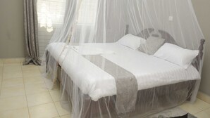 Una cama con dosel, una ventana con cortinas y un suelo de baldosas.