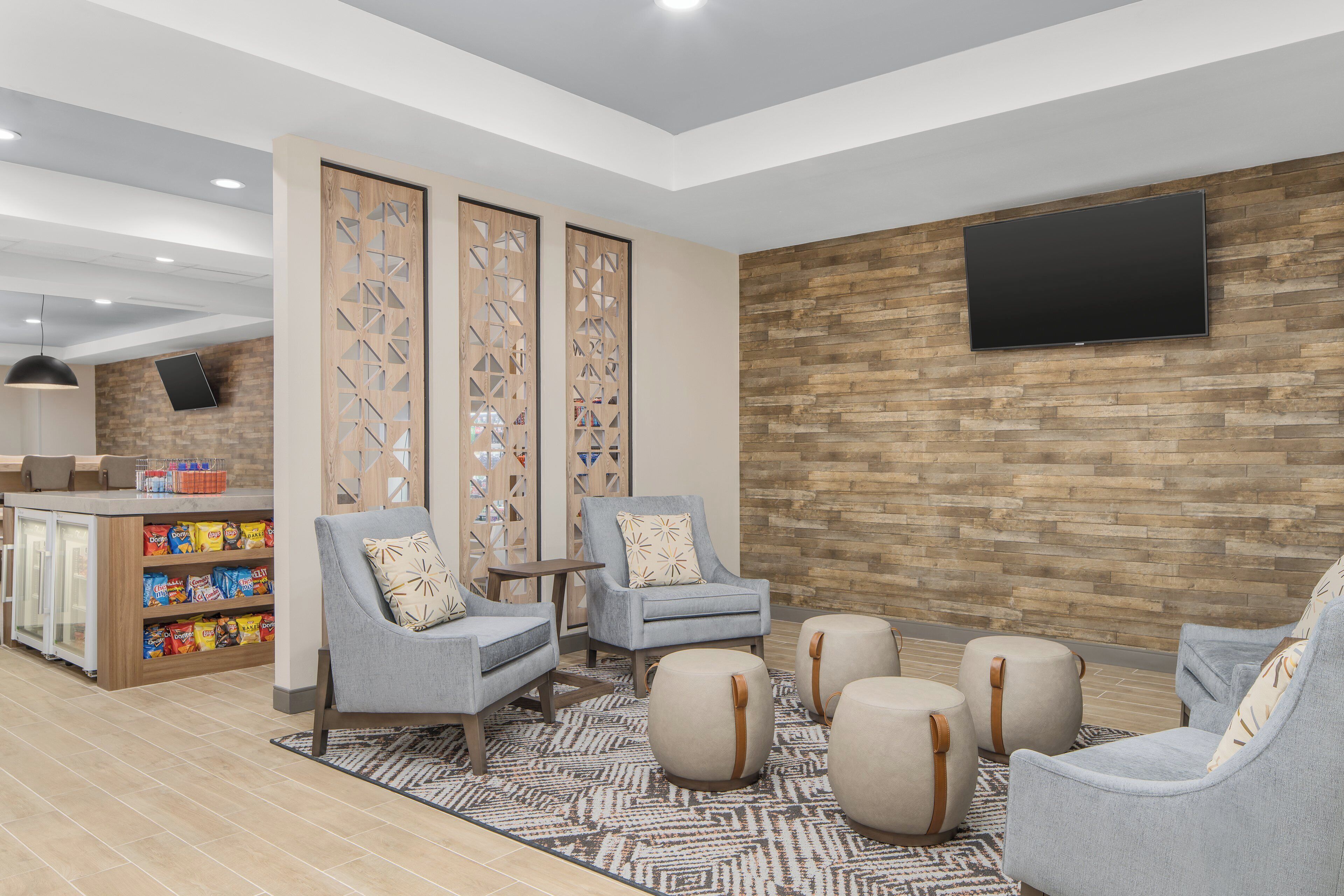 A modern lounge area with seating, a snack bar, and a TV mounted on a stone wall.