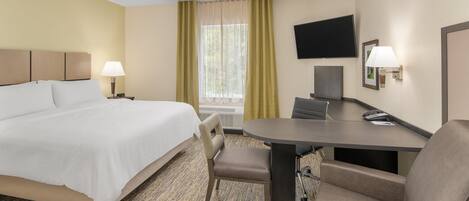 A hotel room with a bed, a desk, a chair, a TV, and a window with curtains.