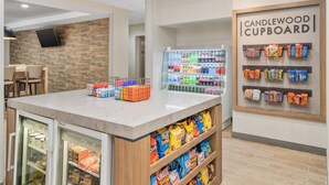 A snack bar area with a refrigerated display, a beverage cooler, and shelves stocked with snacks.