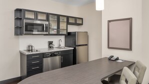 A modern kitchen with a microwave, stove, refrigerator, and a dining area with a table and chairs.