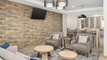 Ett modernt loungeområde med en väggpanel i trä, bekväma sittplatser och hängande lampor.