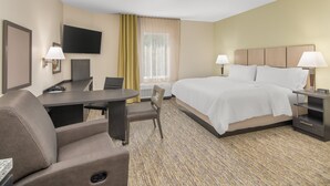A hotel room with a bed, desk, chair, TV, and lamps.