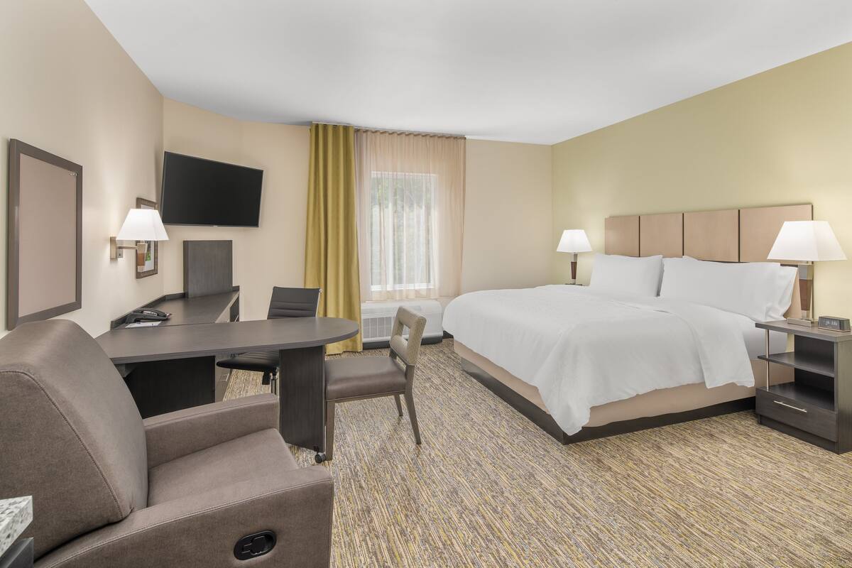 Une chambre d’hôtel équipée d’un lit, d’un bureau, d’une chaise, d’une télévision et de lampes.